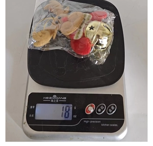Detail shot of a plush reindeer ornament with a gold bell on a digital scale weighing 18g