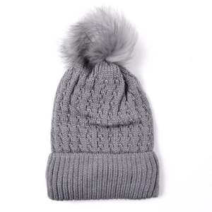 Detail of grey cable knit beanie with fluffy faux fur pompom and wide ribbed cuff edge
