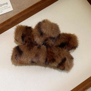 Detailed view of leopard print plush hair claw clip with soft texture on wood background