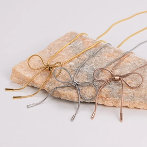 Bow tie necklaces in gold, silver, and rose gold on a textured stone display
