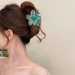 Détail de la pince à cheveux fleurie en résine bleue marbrée portée sur cheveux bruns