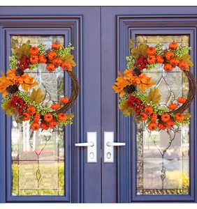 Dual autumn wreaths with pumpkins and red berries displayed on dark blue double doors