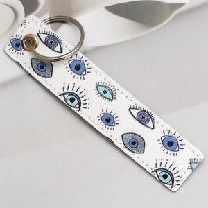 Detailed view of a white PU leather keychain with blue evil eye patterns and metal rings