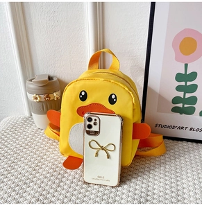 Detail view of mini yellow duck backpack next to a smartphone for size comparison