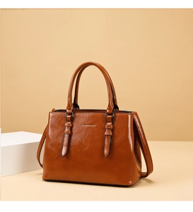 Detail of caramel glossy leather handbag with top handles and adjustable strap