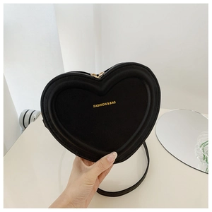 Dettaglio di una borsa a tracolla nera a forma di cuore con finitura in pelle opaca e zip dorata
