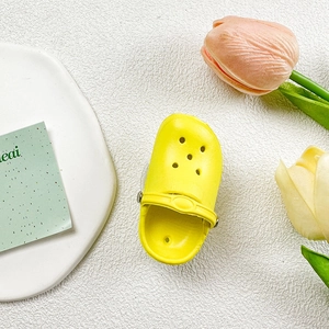 Detailed close-up of a bright yellow slipper-shaped phone grip on a white texture background