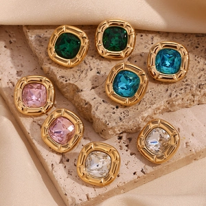 Detail of vintage square crystal earrings in gold alloy settings on stone surface