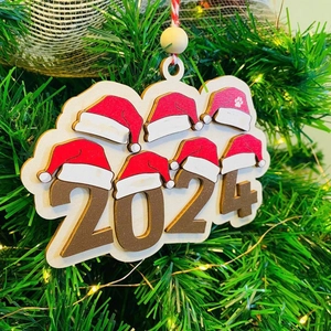 Close-up of wooden 2024 Christmas ornament with a red Santa hat on a pine tree