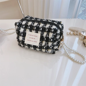 Close-up of black and white tweed cosmetic bag with gold metallic threads and pearl handle