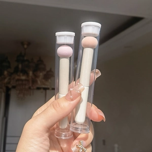 Macro view of mushroom head concealer sponges with beige handles in a clear tube