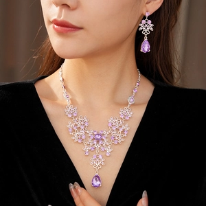 Close-up of vintage floral necklace and earring set with purple crystals on a model