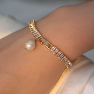 Détail d'un bracelet vintage en or avec zircons brillants et une perle blanche