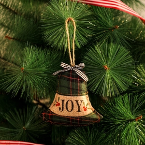 Détail d'ornement de cloche de Noël en lin avec imprimé Joy sur branche de sapin