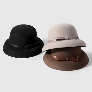 Close-up of three elegant silk linen cloche hats with bow details in black, beige and brown