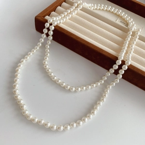 Detail shot of multi-layered white faux pearl necklace draped on a jewelry box