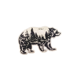 Embroidered black and white bear patch featuring forest landscape for outdoor gear