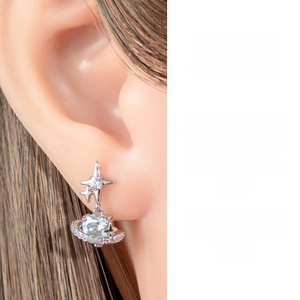 Macro shot of silver star and blue planet piercing stud worn on ear cartilage