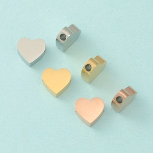 Detail of heart-shaped metal beads in silver, gold, and rose gold with side holes
