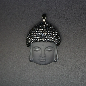 Macro view of crystal Buddha head pendant with black rhinestones and gold-tone trim