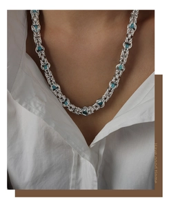 Macro view of punk dragon bone chain necklace with blue gemstone accents on model