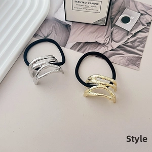 Detail of gold and silver textured metal hair ties set on a white decorative tray