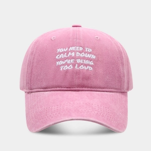 Detail of pink washed cotton baseball cap featuring white slogan embroidery and stitching