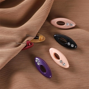Close-up of colorful oval resin scarf clips with rhinestones on brown fabric