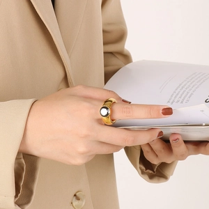 Detail of a wide gold ring with a large black round gemstone on model's finger