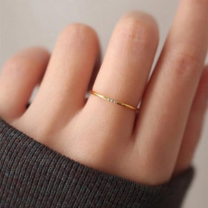 Minimalist ultra-thin gold ring with three sparkling diamonds worn by a model