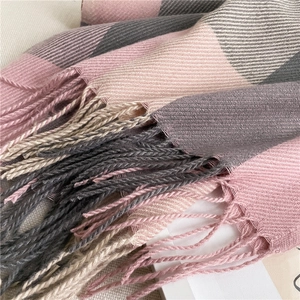 Close-up detail of soft plaid scarf texture with elegant fringes in pink and gray tones
