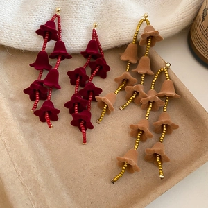 Détail de boucles d'oreilles longues à pampilles en velours muguet rouge et kaki