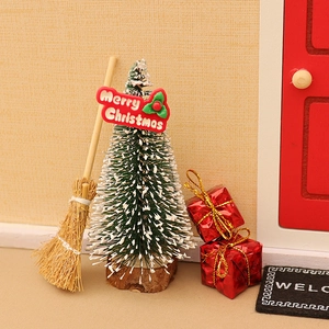 Miniature Christmas dollhouse scene with green tree, wooden broom and red gift boxes