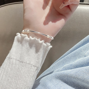 Detailed view of baroque pearls and silver tube elastic bracelet on a woman's wrist