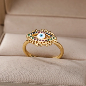 Close-up of golden evil eye ring with colorful zircon inlay in a beige jewelry box