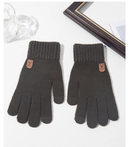 Detailed close-up of dark olive green knit winter gloves with brown leather logo patch