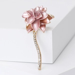 Elegant pink enamel lotus brooch with gold-plated diamond-set stem on white podium
