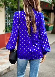 Detail of blue long-sleeve blouse with golden polka dots and elegant puff sleeves