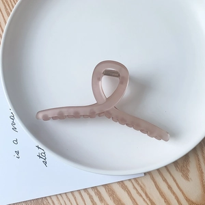 Détail d'une grande pince à cheveux rose mat au design profilé et épuré