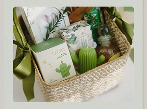 Panier cadeau détaillé contenant une bougie parfumée en forme de cactus avec rubans