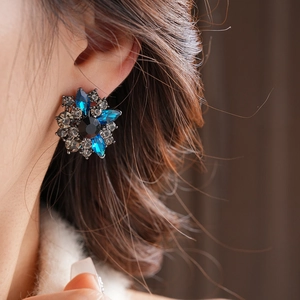 Primo piano di orecchini vintage a fiore con cristalli blu e grigi su una modella