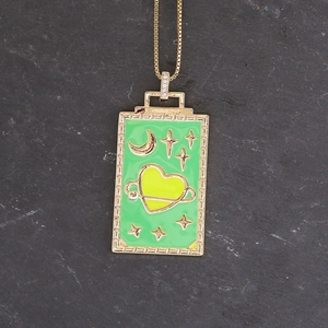 Detail of gold square pendant with green enamel, yellow heart planet and star charms