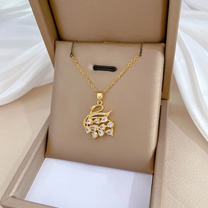 Detailed close-up of a gold swan pendant necklace inlaid with sparkling crystals in a box