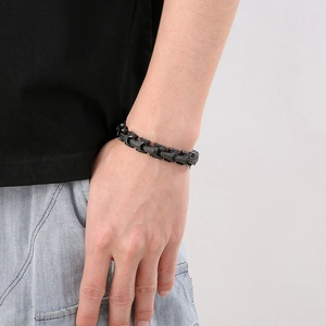 Close-up of punk style dragon scale chain bracelet on male wrist in matte black finish