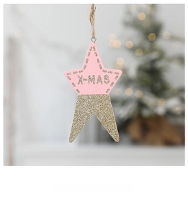 Detail of pink and gold wooden star ornament with glitter and X-MAS text on tree