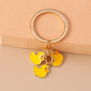 Detailed shot of golden keychain featuring three cute yellow cartoon duck charms