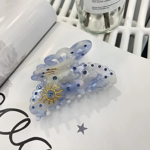 Pince à cheveux nuage avec dégradé bleu, strass et motif soleil doré sur un livre