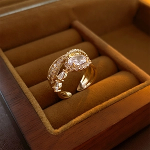 Detail of gold multilayer open ring with oval cubic zirconia on dark jewelry box