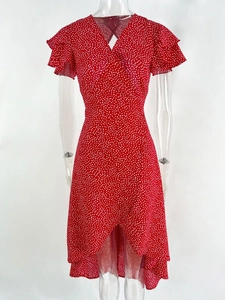 Detail of red polka dot dress featuring a V-neckline and ruffle sleeves on white background