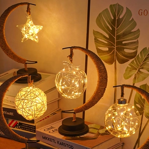Detail of warm LED moon lamps with star and apple pendants in rustic twine iron frames
